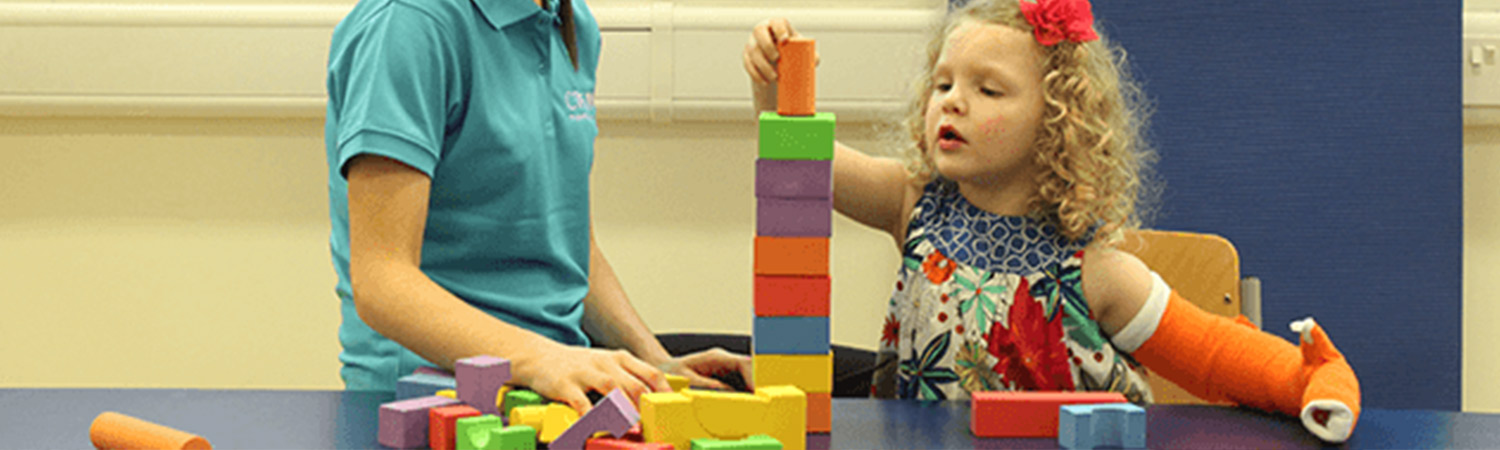 Child stacking blocks with her hand in a CIMT cast Child stacking blocks with her hand in a CIMT cast