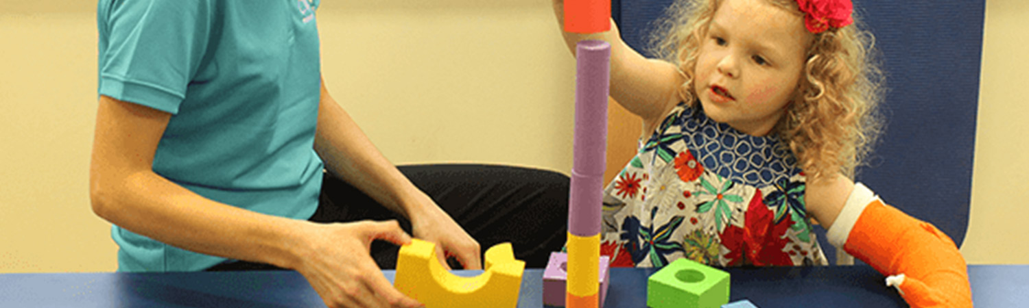 Child stacking blocks with her hand in a CIMT cast Child stacking blocks with her hand in a CIMT cast