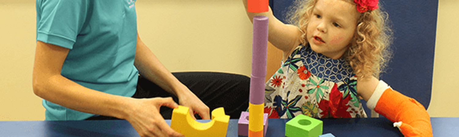 Child learning to balance cylindic blocks on top of each other.