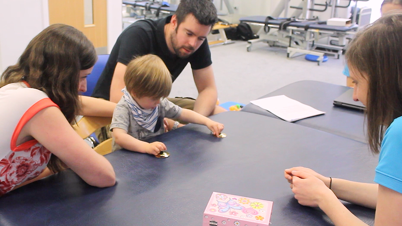 Alistair playing with his mum, dad and therapist.