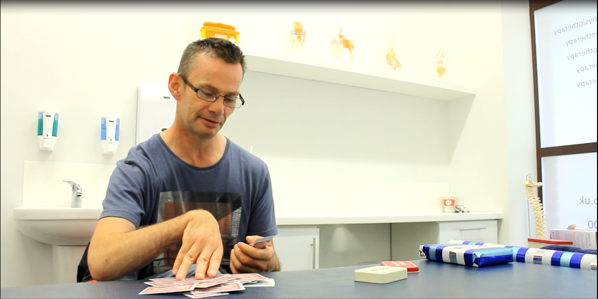 Andrew picking up a deck of cards using weaker hand.