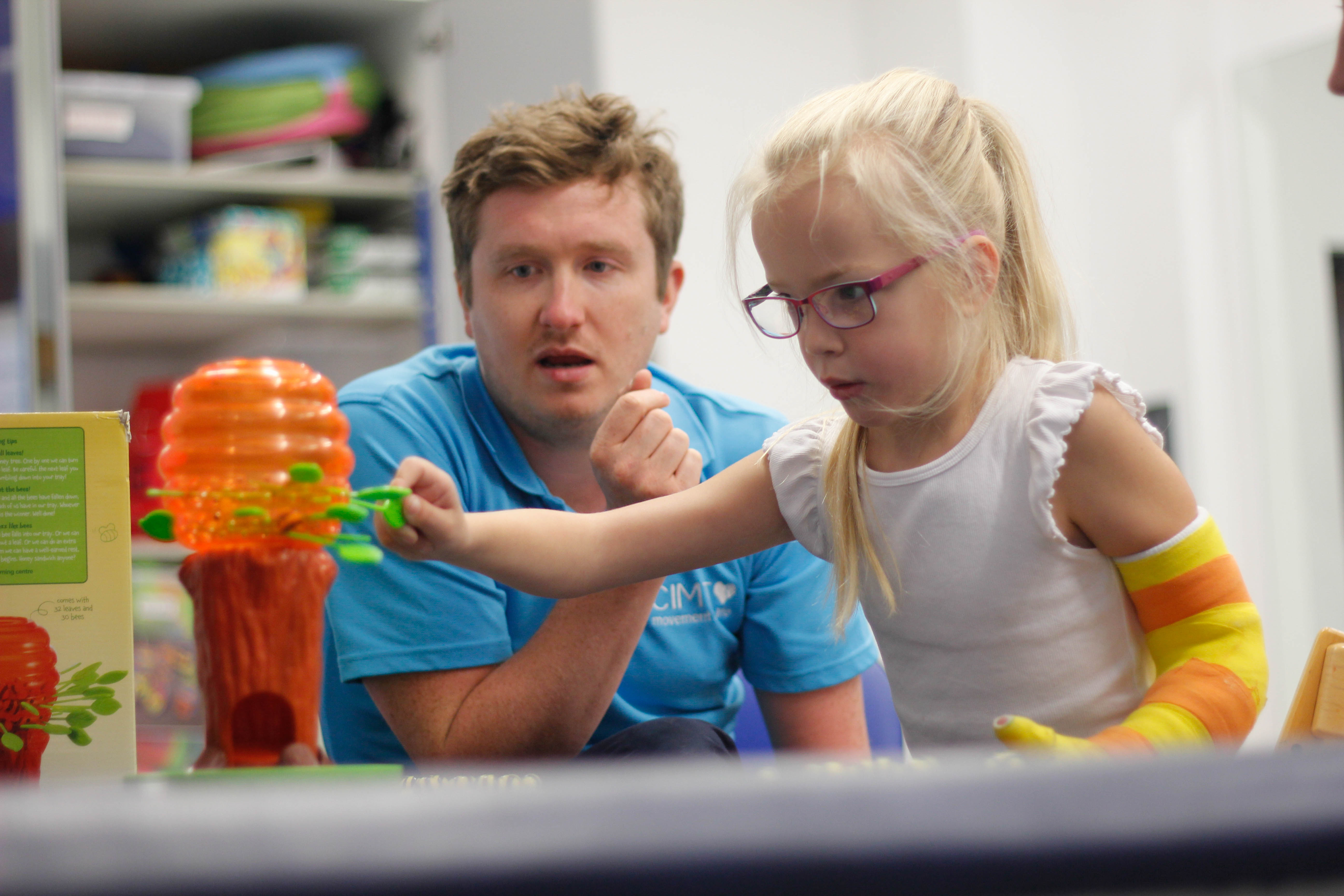 Darcie reaching out for toy with CIMT therapist.