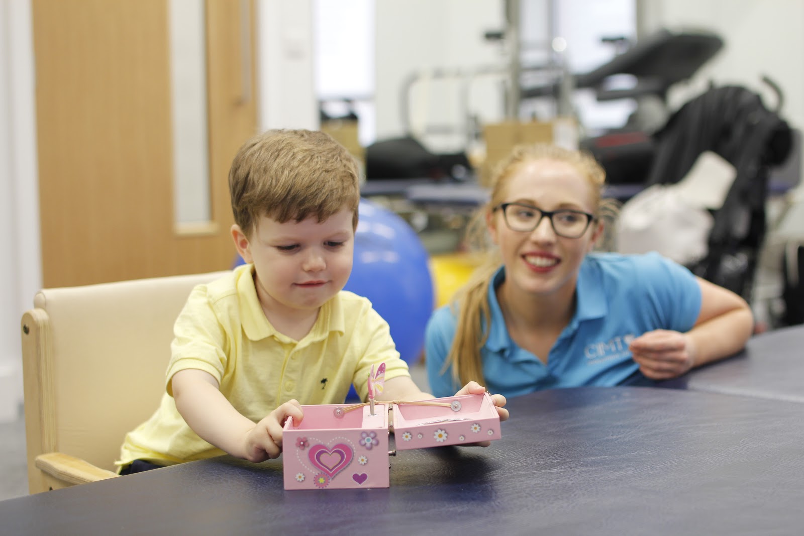 Finlay playing with toy box with assistance from CIMT therapist.