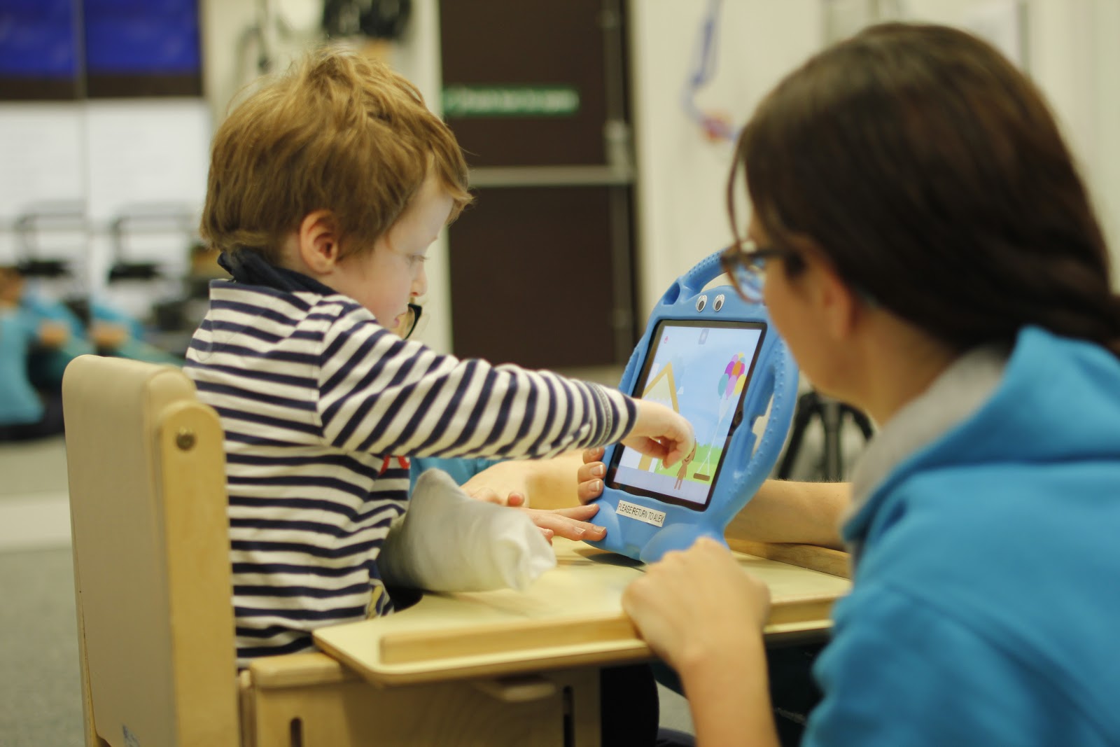 Freddie interacting with tablet with CIMT therapist