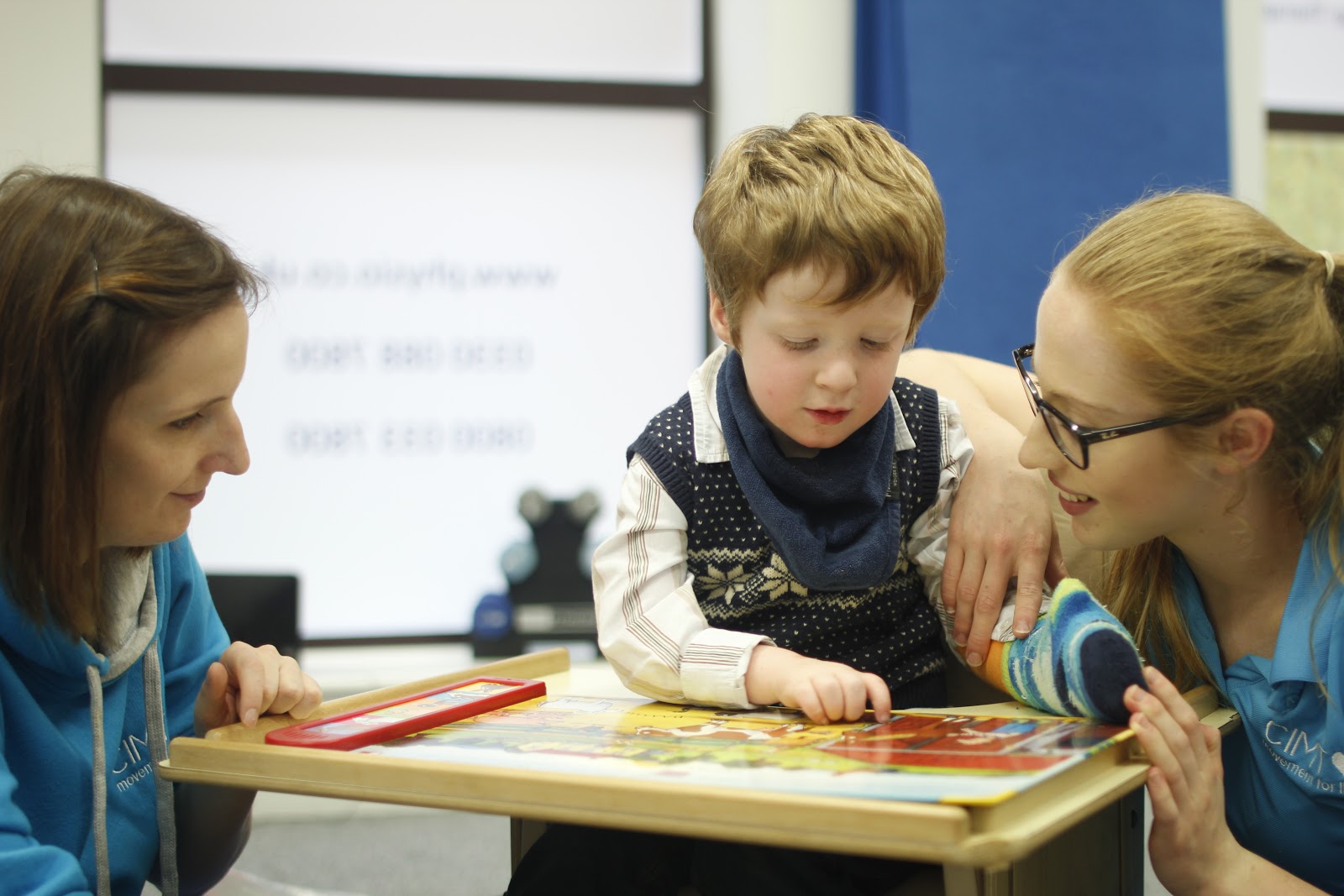 Freddie interacting with CIMT therapists with cast.