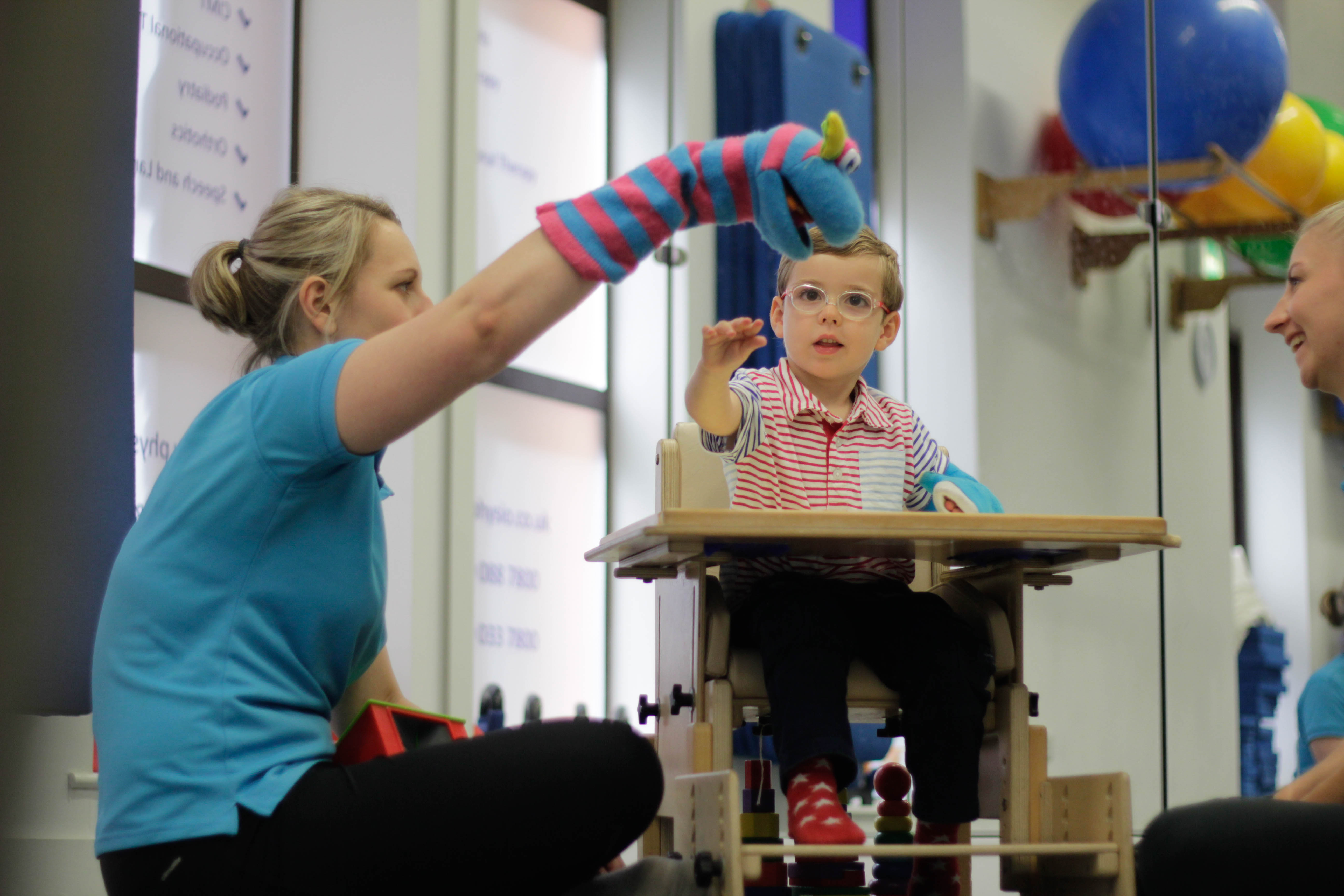 George reaching out for toy with CIMT therapist.