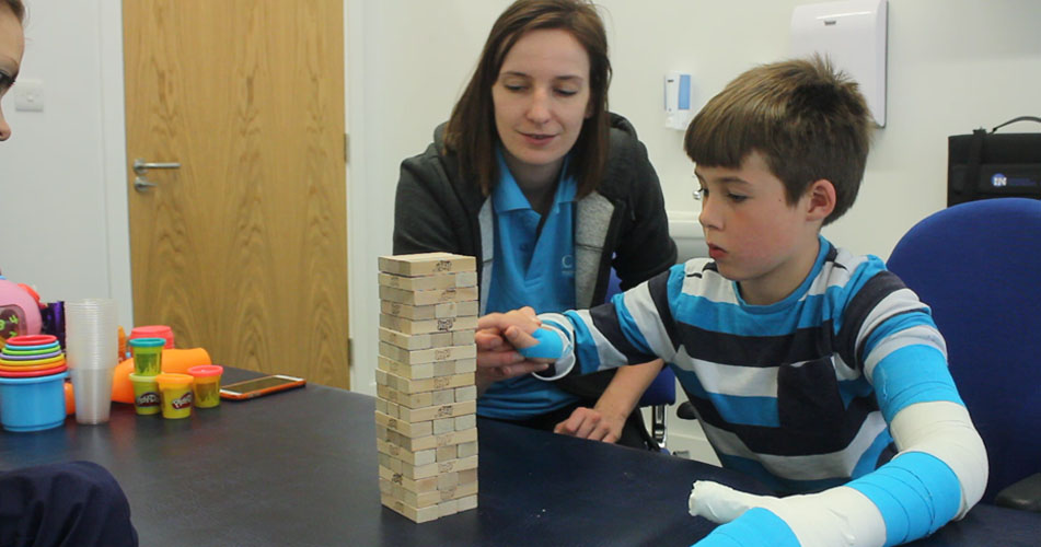 Harvey using his weaker arm to remove a jenga block.