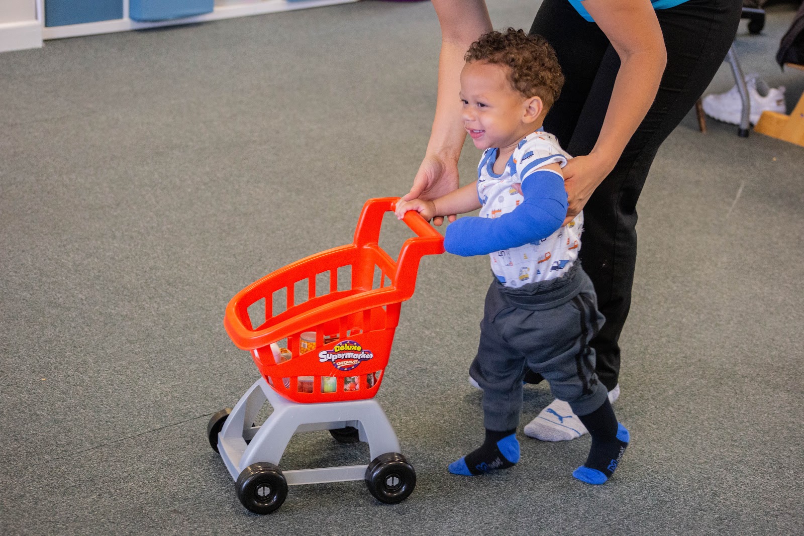 Kaiden pushing toy trolley.