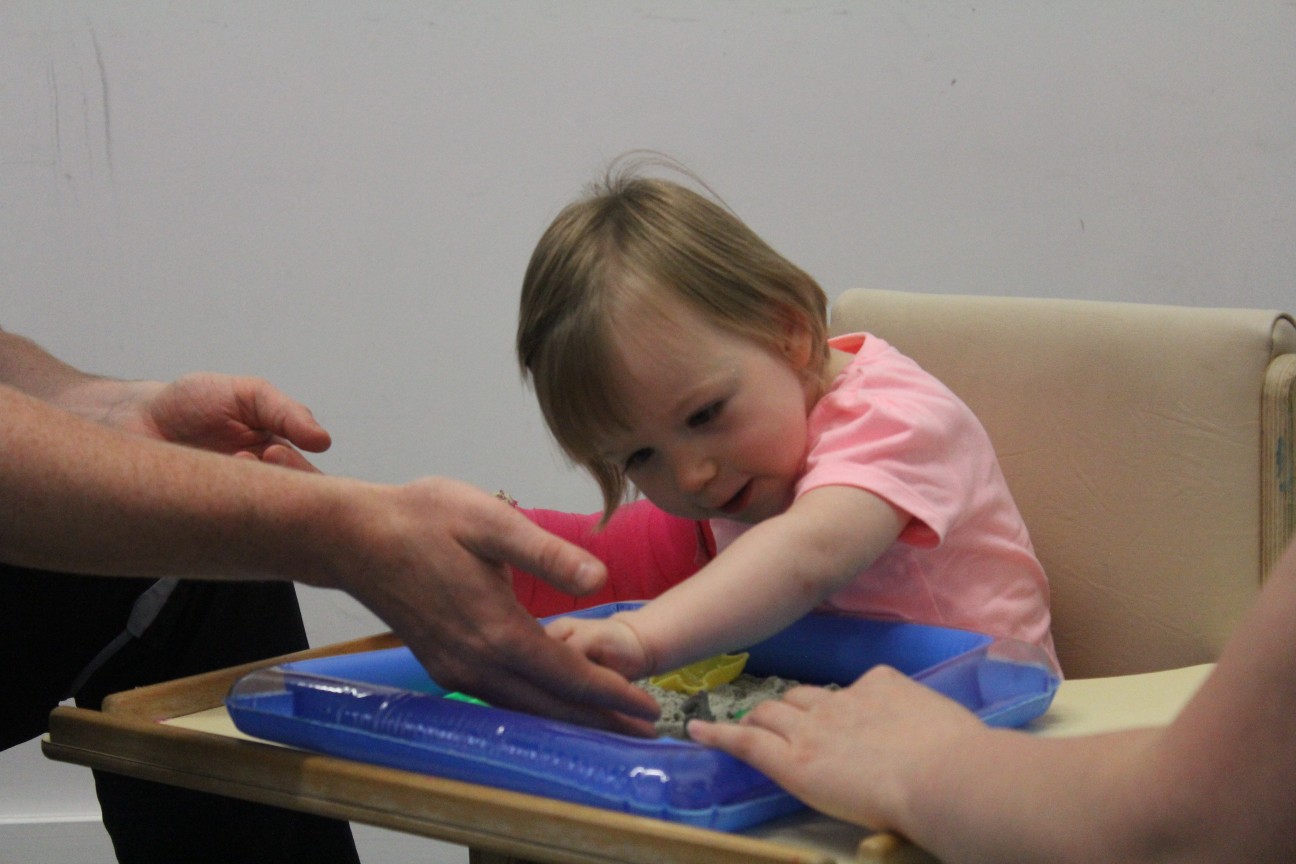 Leah bieng shown how to use the toys during CIMT treatment