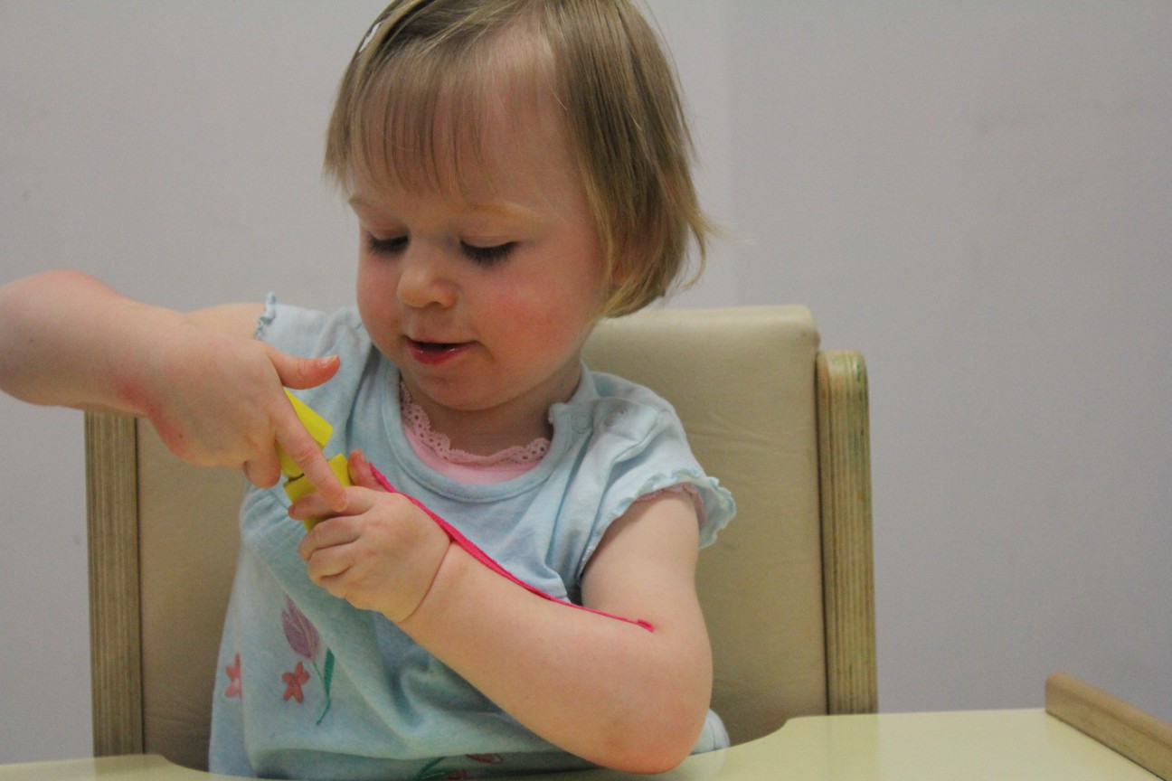 Leah playing with a toy with CIMT therapists