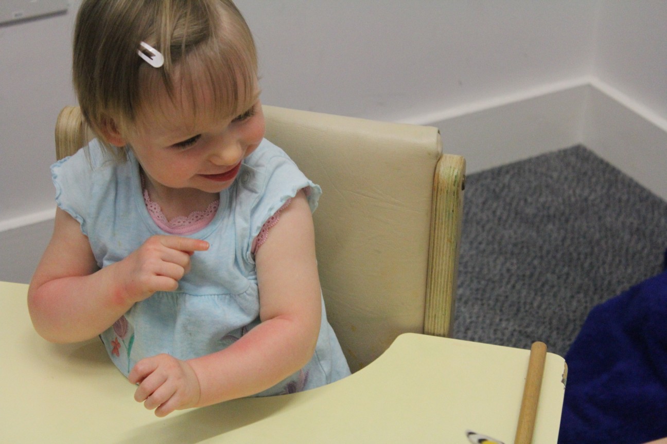 Leah reaching out for toy with CIMT therapist.