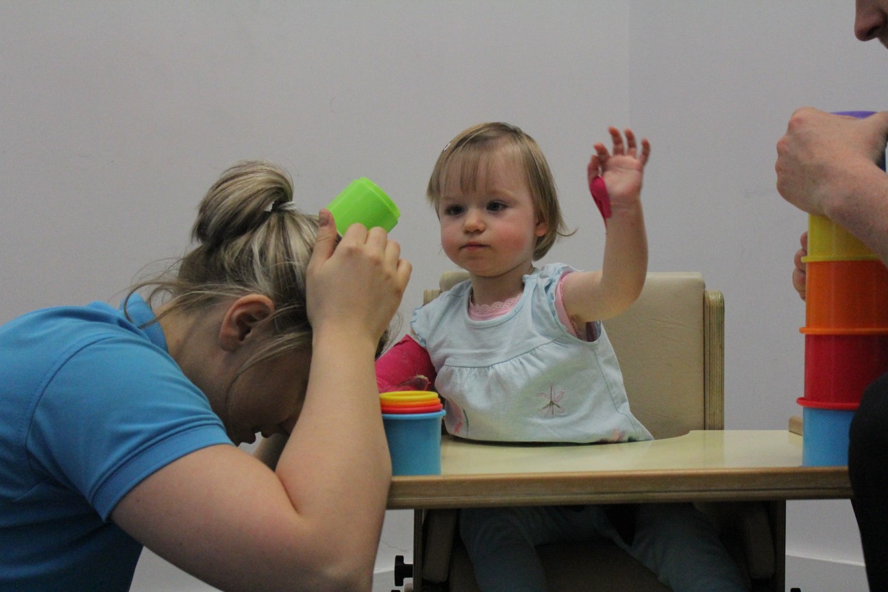Leah playing with toys with CIMT therapists.