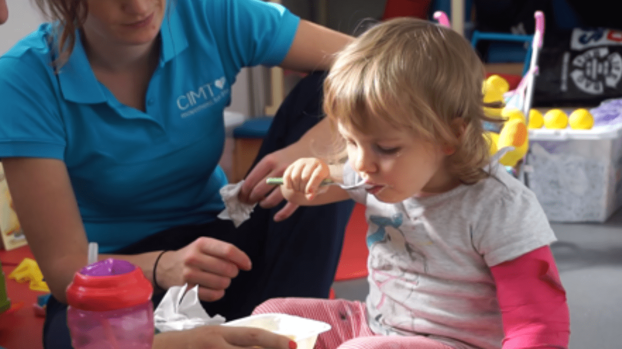 Lottie using a spoon to feed herself.