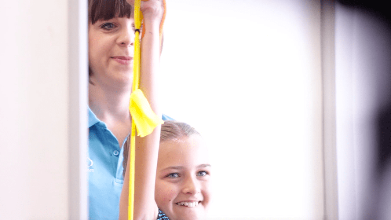 Lydia reaching upwards with resistance band.