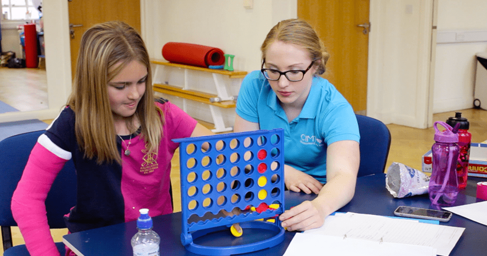 Lydia and her therapist playing Connect 4 and concentrating.