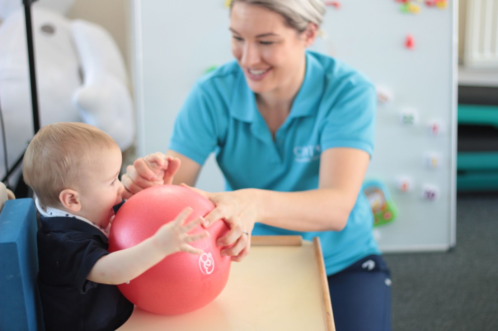 Myles holding a ball in his hands with therapist.