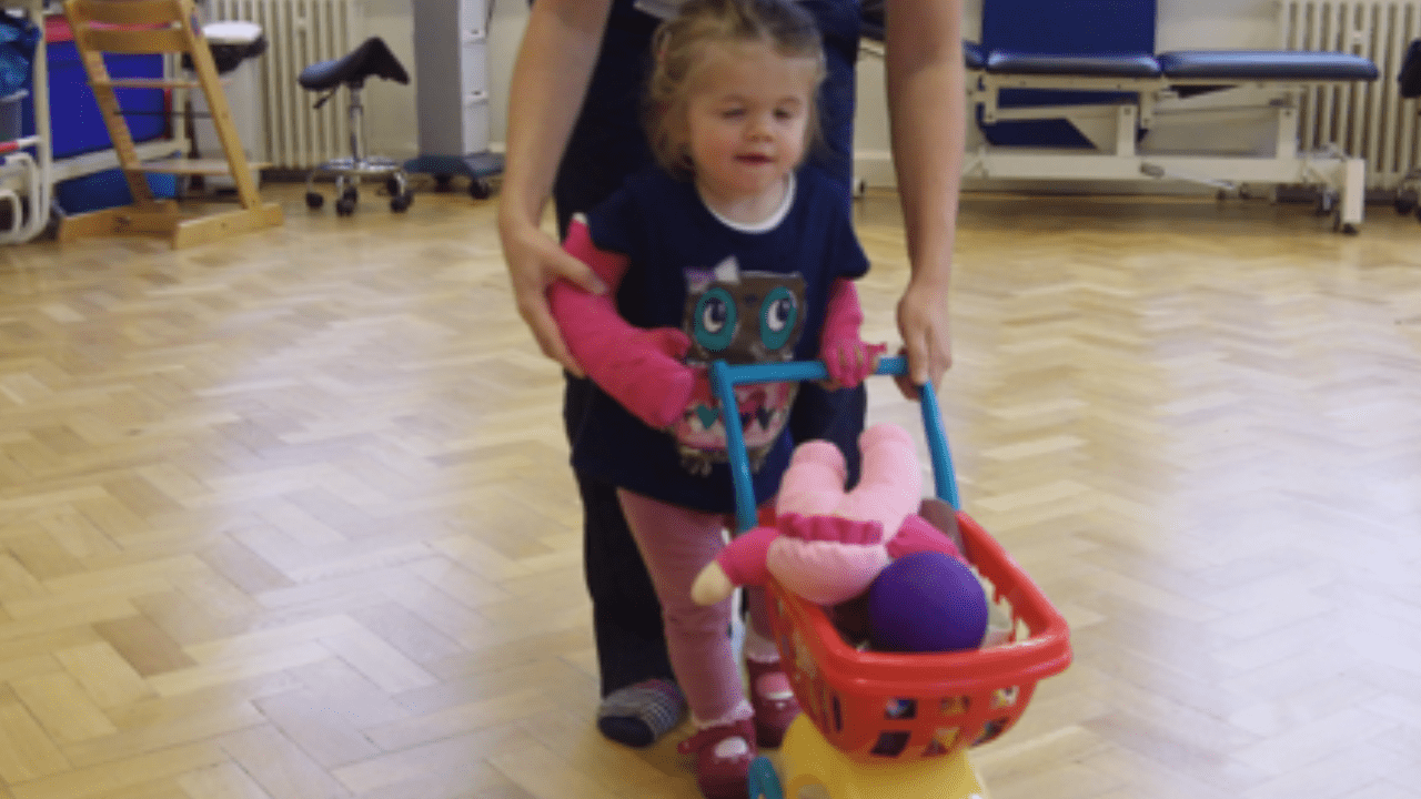 Olivia practises pushing a trolley with some assistance.