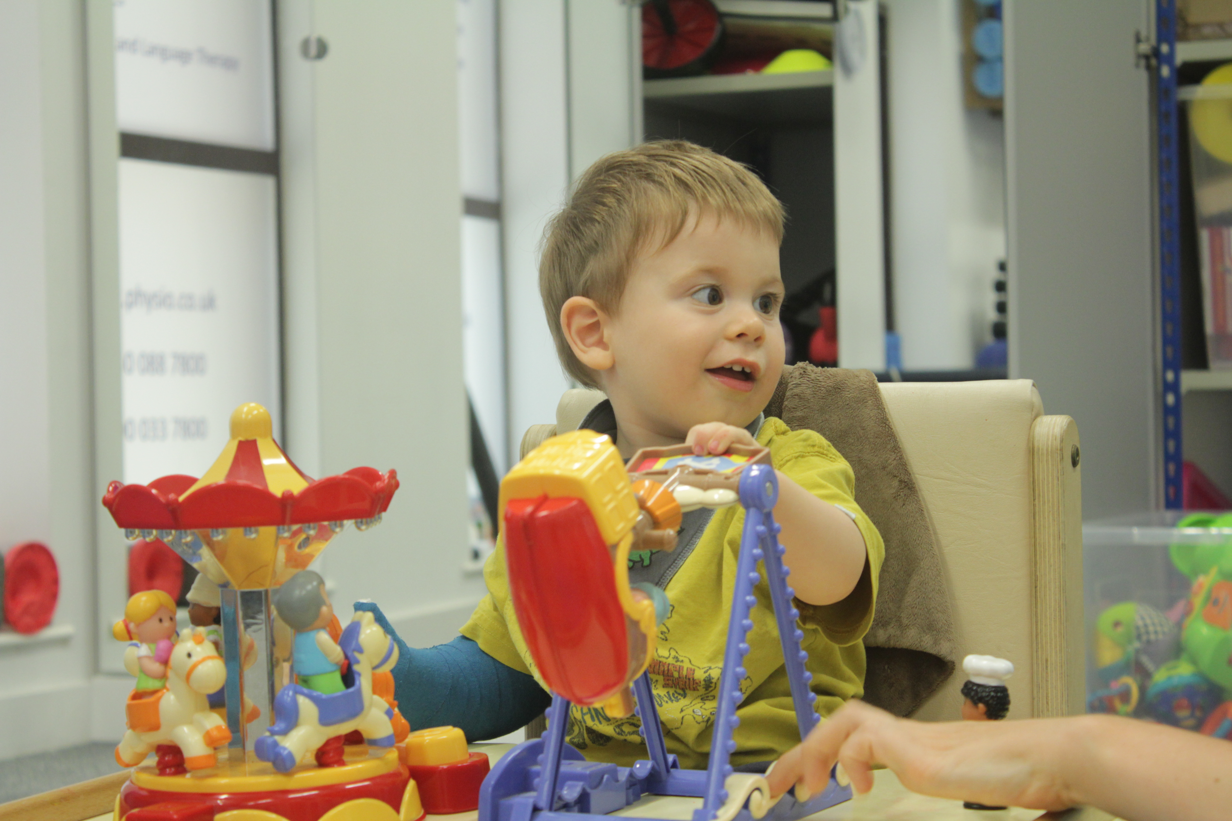 Thomas looking over at CIMT therapist during treatment.