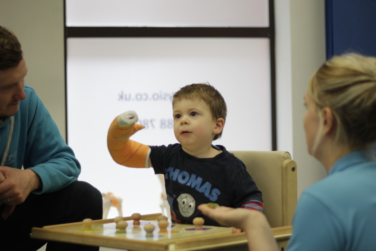 Thomas guided by CIMT therapist during treatment.