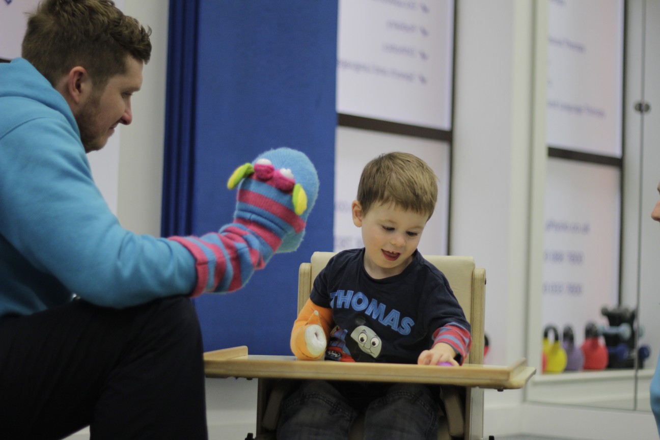 Thomas looking over at CIMT therapist during treatment.